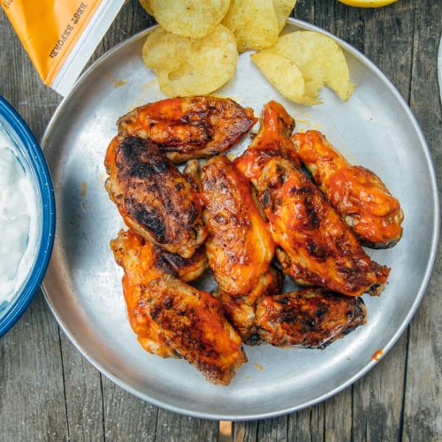 Grilled buffalo wings on a plate with potato chips