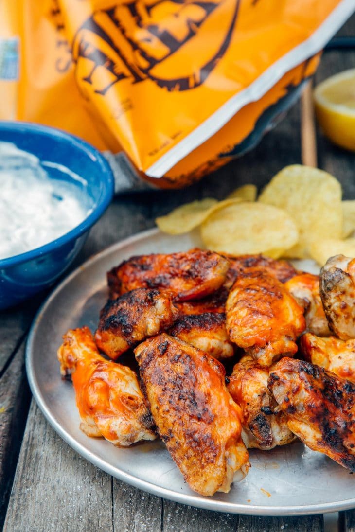 Grilled buffalo wings on a silver plate with potato chips