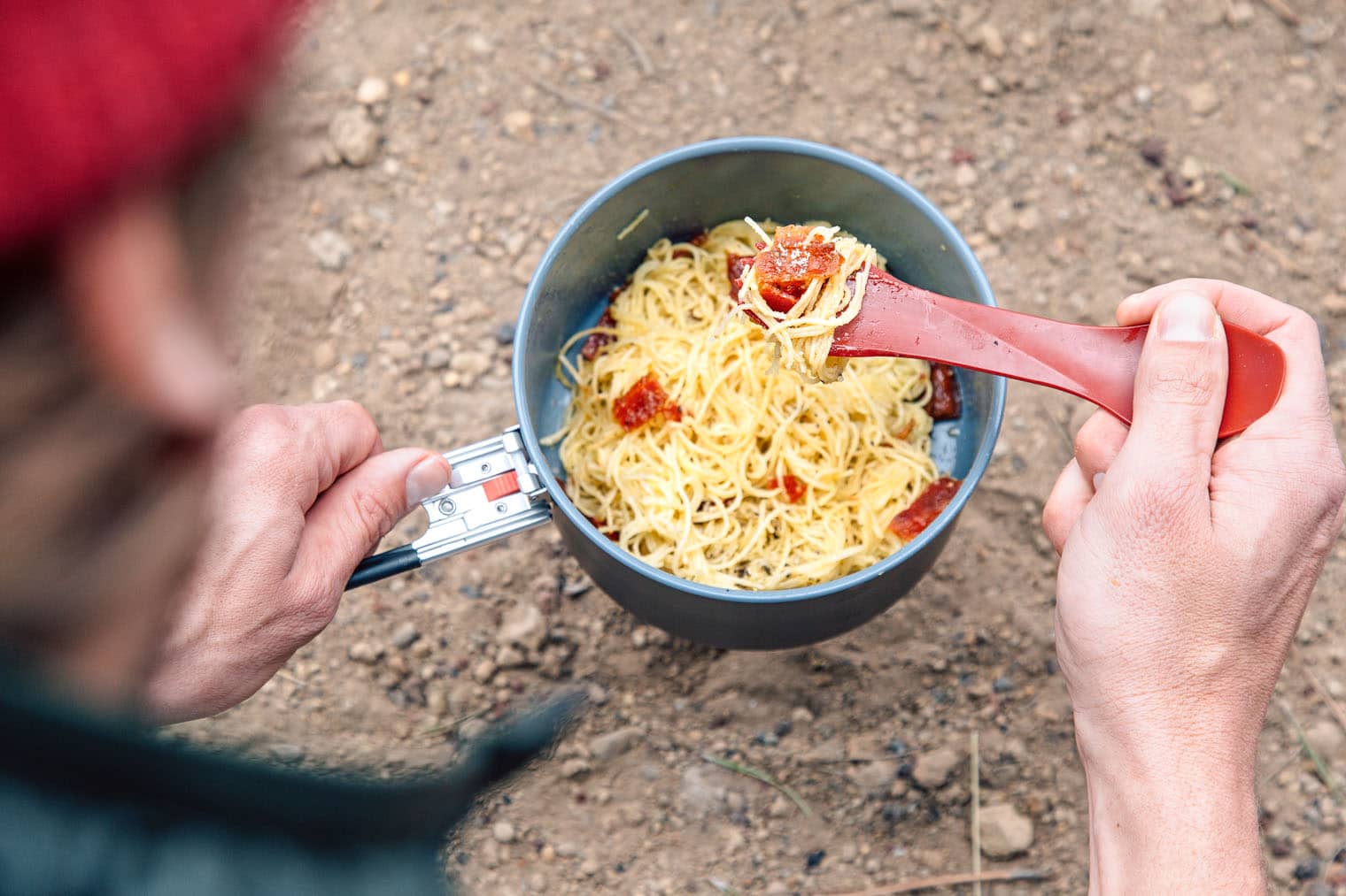 Michael picking up a forkful of pasta from a backpacking pot