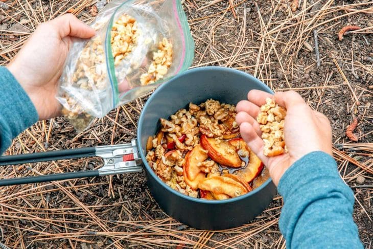 Megan adding granola from a bag to a pot of apples