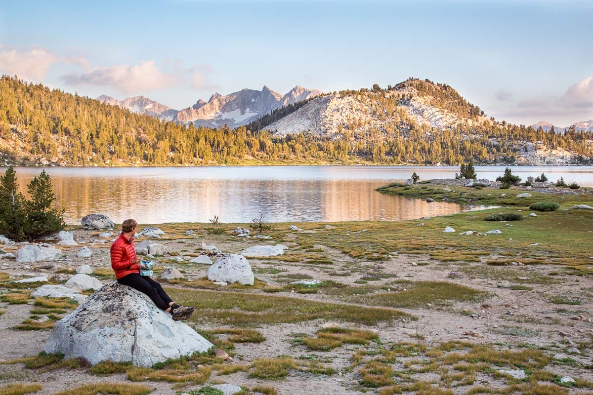 Michael sitting on a rock with a lake and mountains in the background