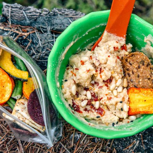 Hummus in a green backpacking bowl on a rock