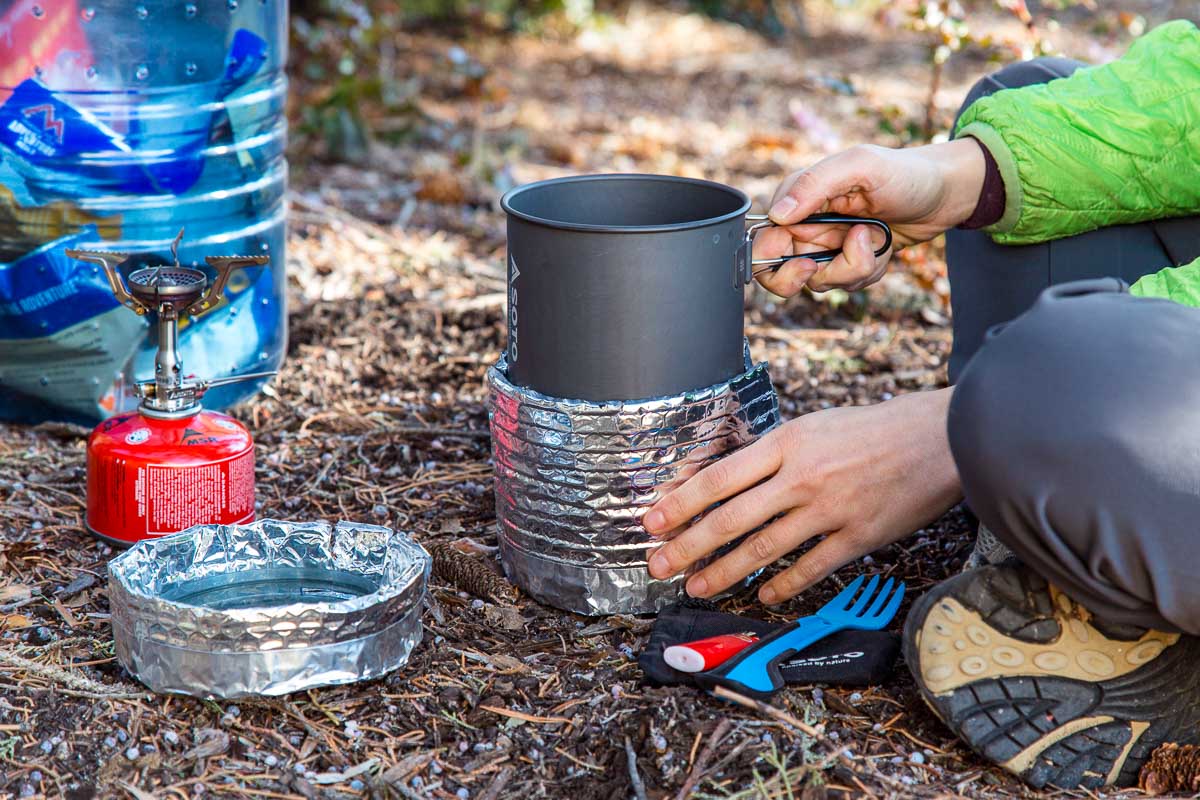 Megan placing a pot into a backpacking pot cozy