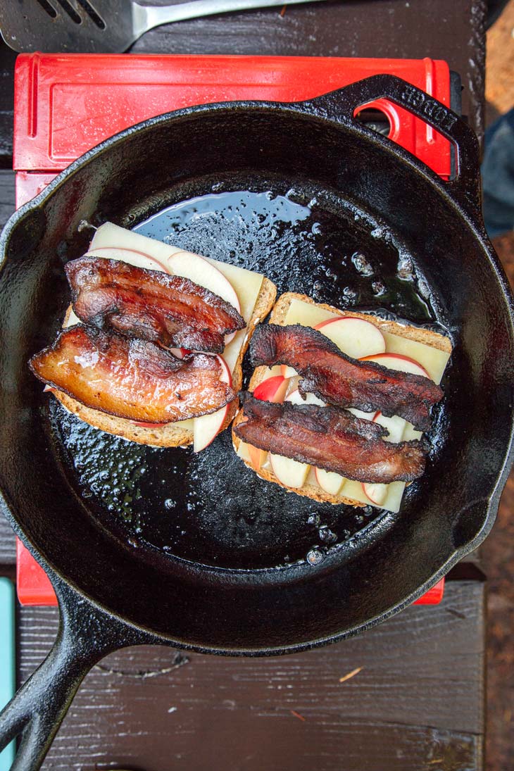 Bread layered with cheese and fried bacon in a skillet