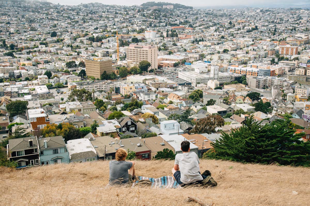 Michael and a friend sitting on Bernal Hill overlooking the city of San Francisco