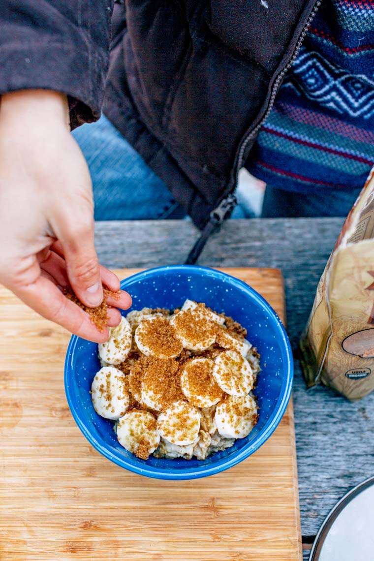 Megan sprinkling brown sugar on top of sliced bananas