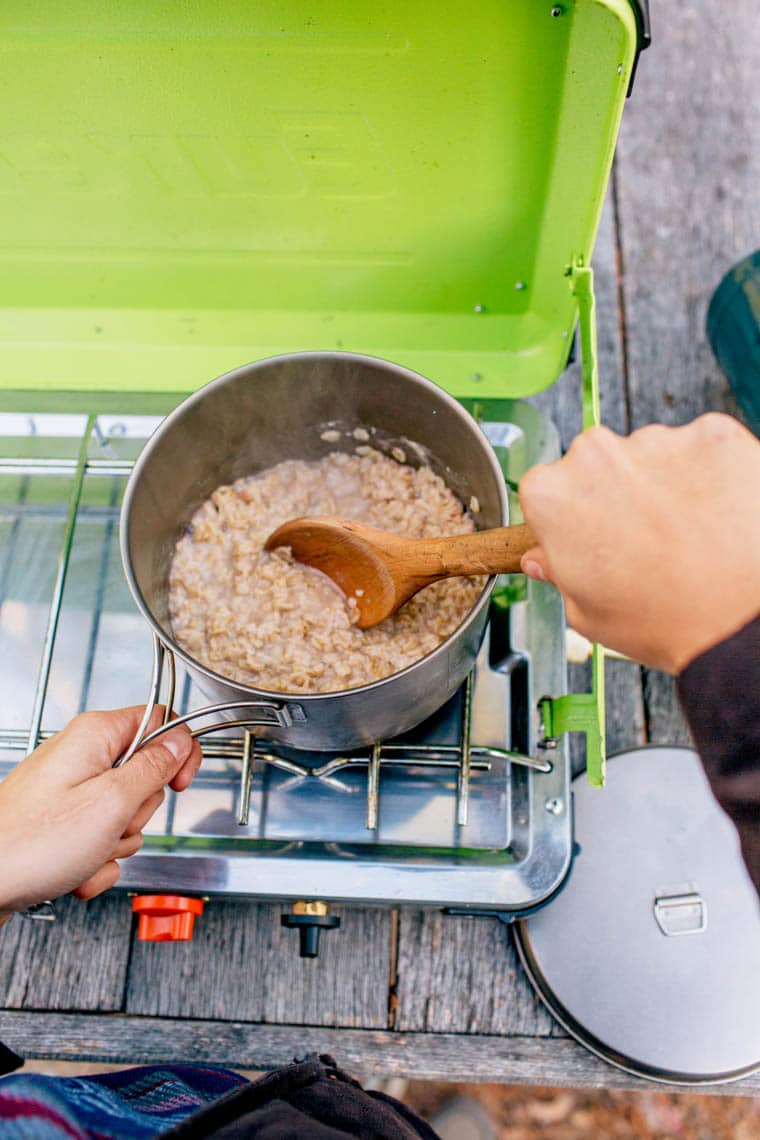 Megan cooking oatmeal over a camping stove