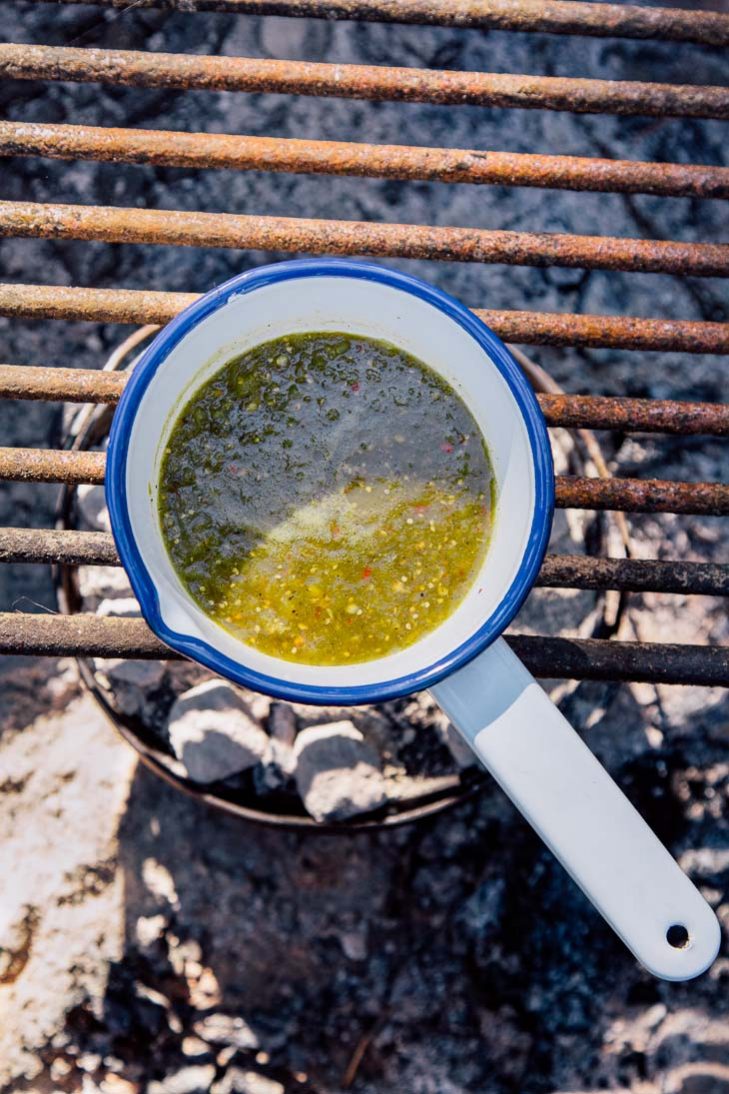 A small pot of salsa verde over a campfire