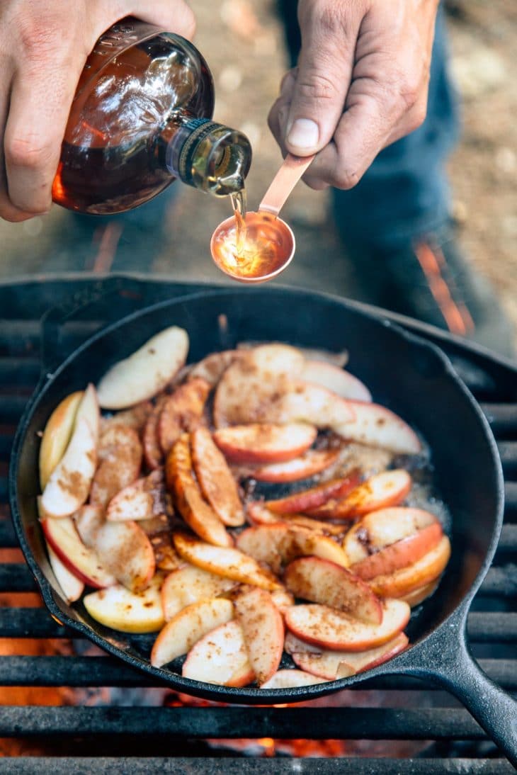 Adding ingredients into a skillet filled with apples