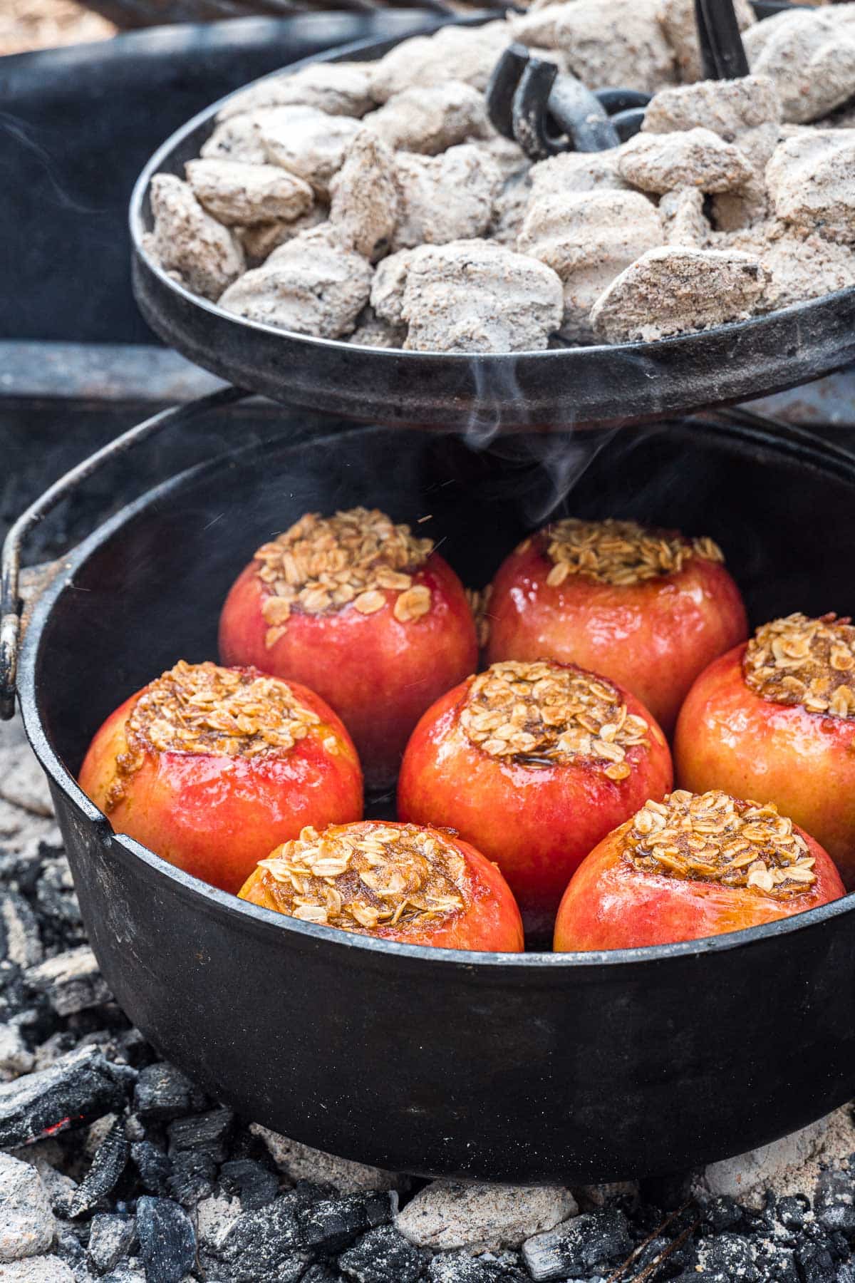 The lid of a dutch oven being removed to reveal cooked apples.