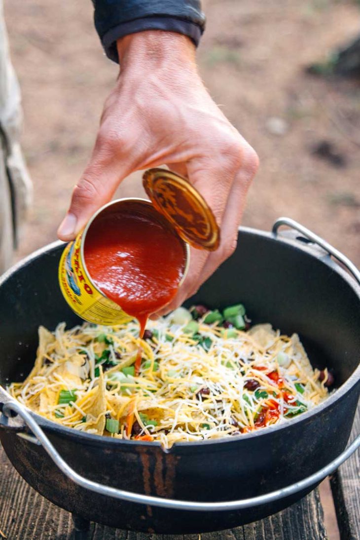 Michael pouring salsa into a Dutch oven