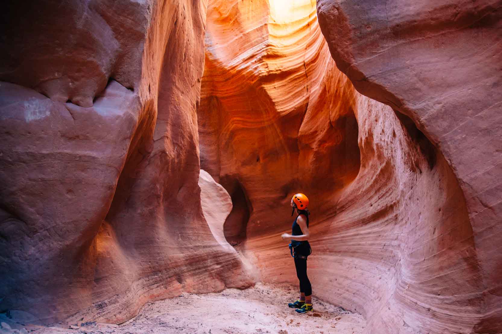 Megan looking up at the walls of a pink and orange slot canyon