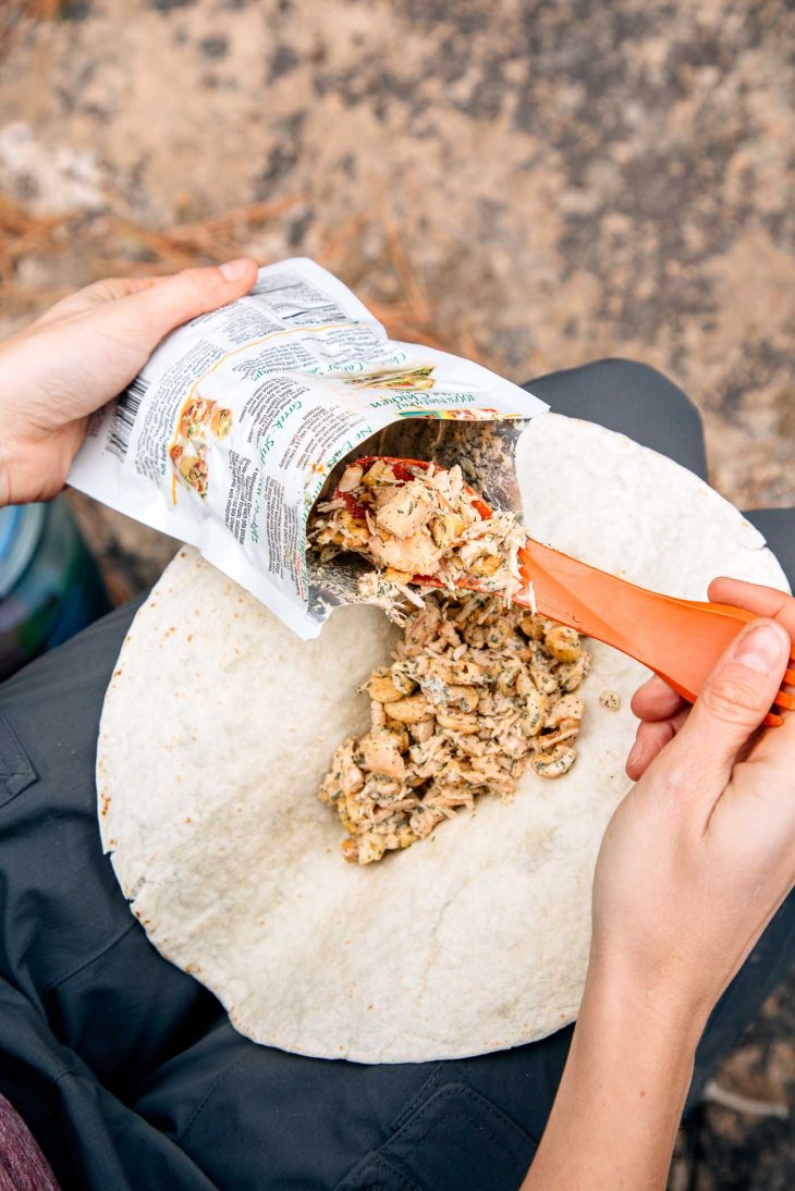 Filling a tortilla with cashew chicken salad