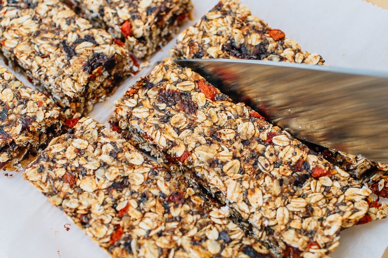 A knife slicing homemade granola bars into bars