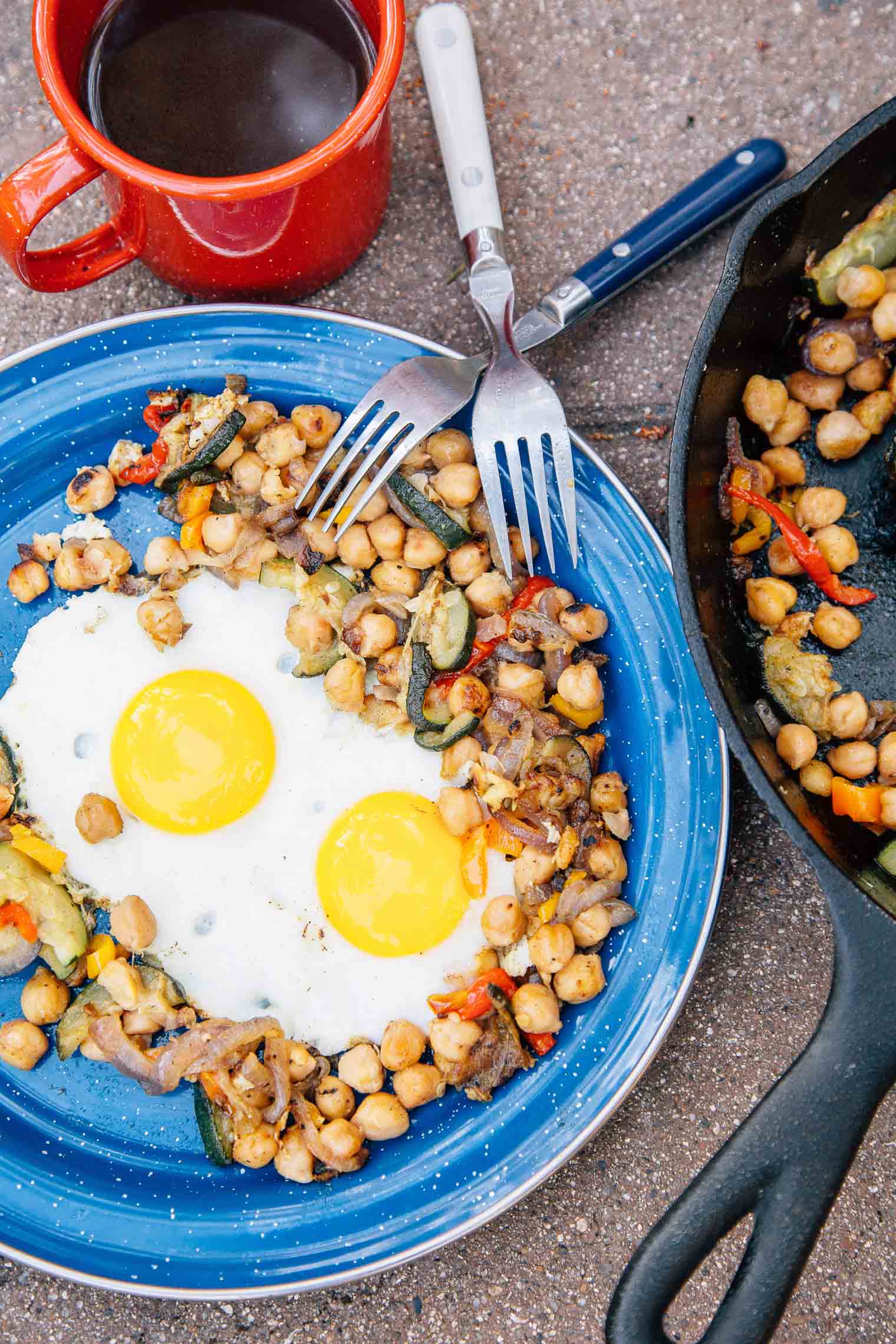 Chickpea hash with two eggs on a blue plate next to a cast iron skillet