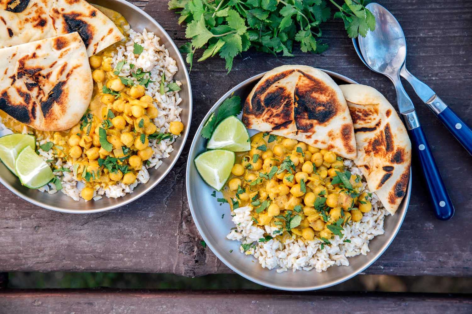 Two plates of coconut chickpea curry over rice on a camping table.