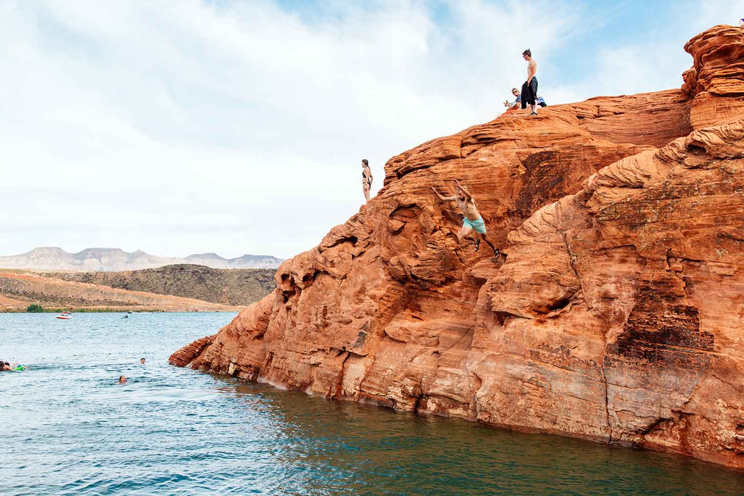 Michael jumping off a tall rock outcropping into the lake at Sand Hollow State Park