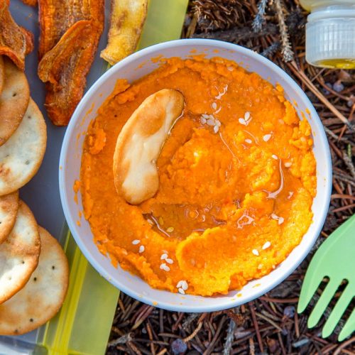 Hummus in a bowl next to crackers and a spork