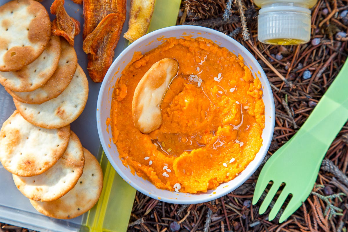 Hummus in a bowl next to crackers and a spork