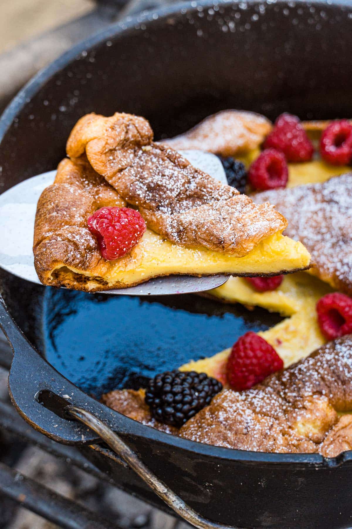 Lifting a slice of Dutch baby out of a dutch oven