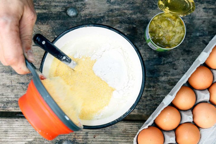 Adding ingredients for cornbread into a large bowl