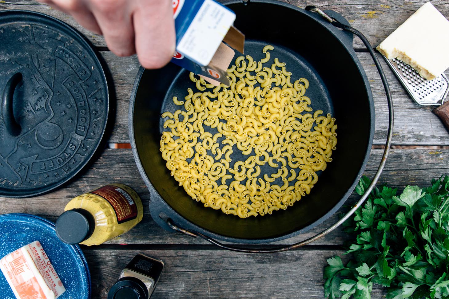 Adding elbow pasta to a Dutch oven for mac and cheese.