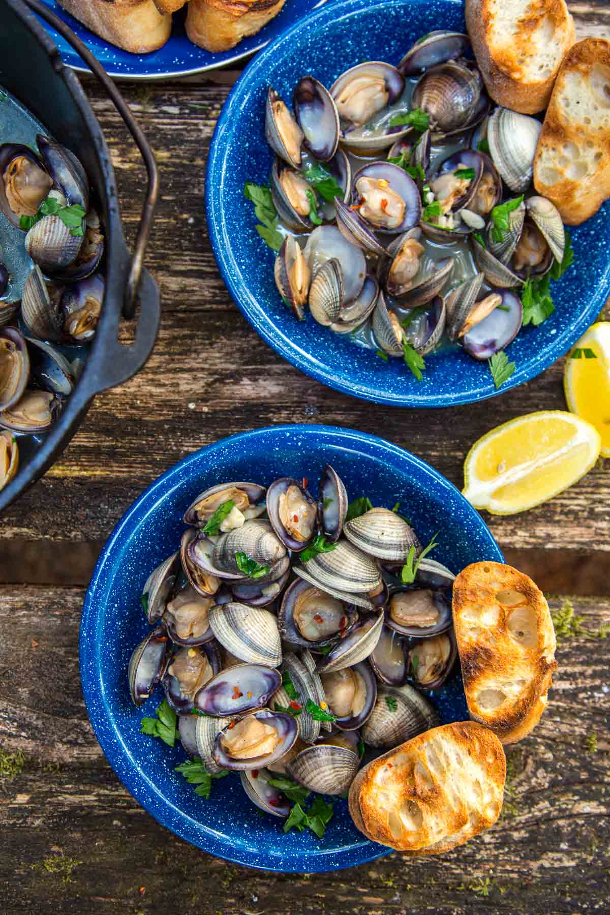 Two bowls with clams and grilled bread on a camp table