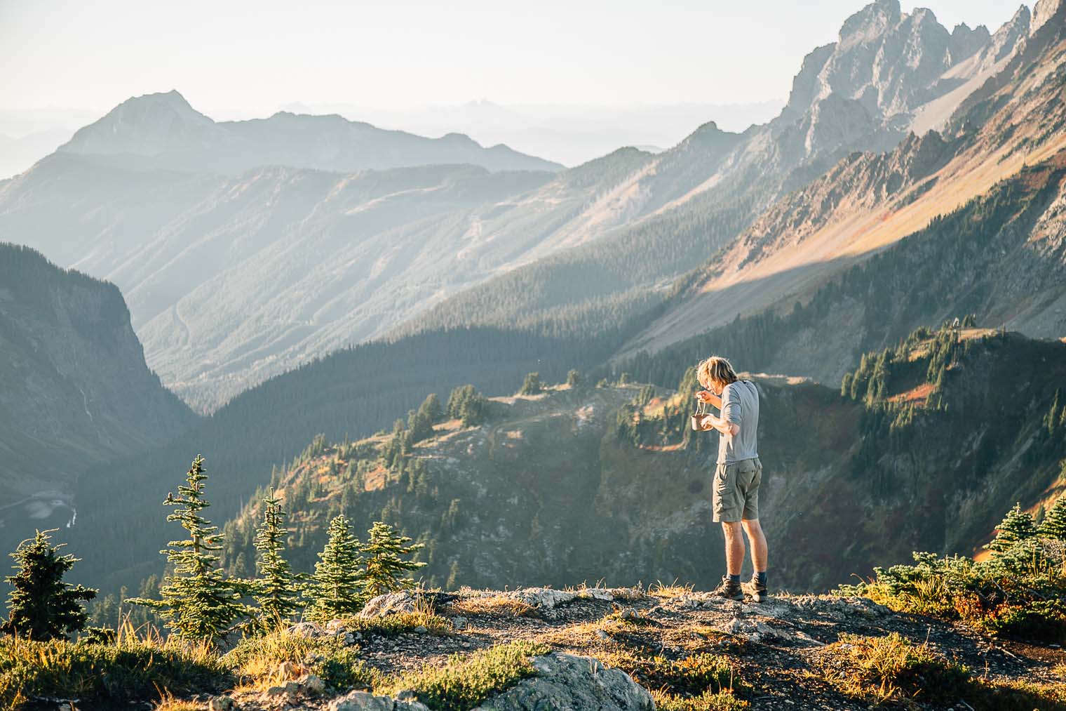 Michael eating out of a backpacking pot with mountains in the distance