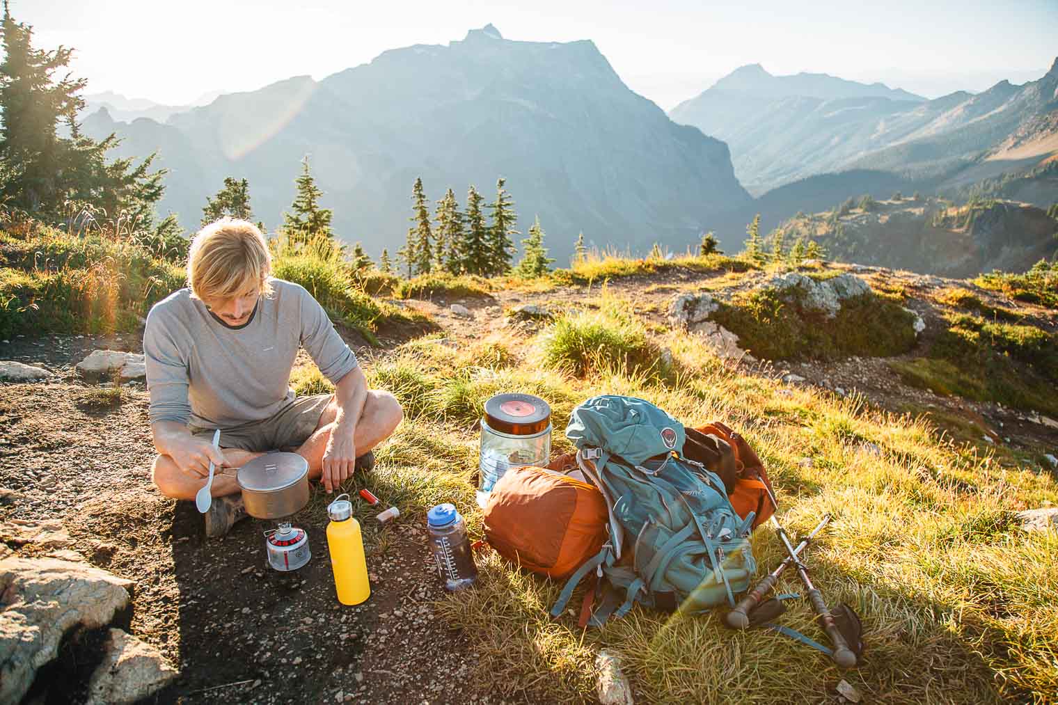 Michael cooking over a backpacking stove with mountains in the background