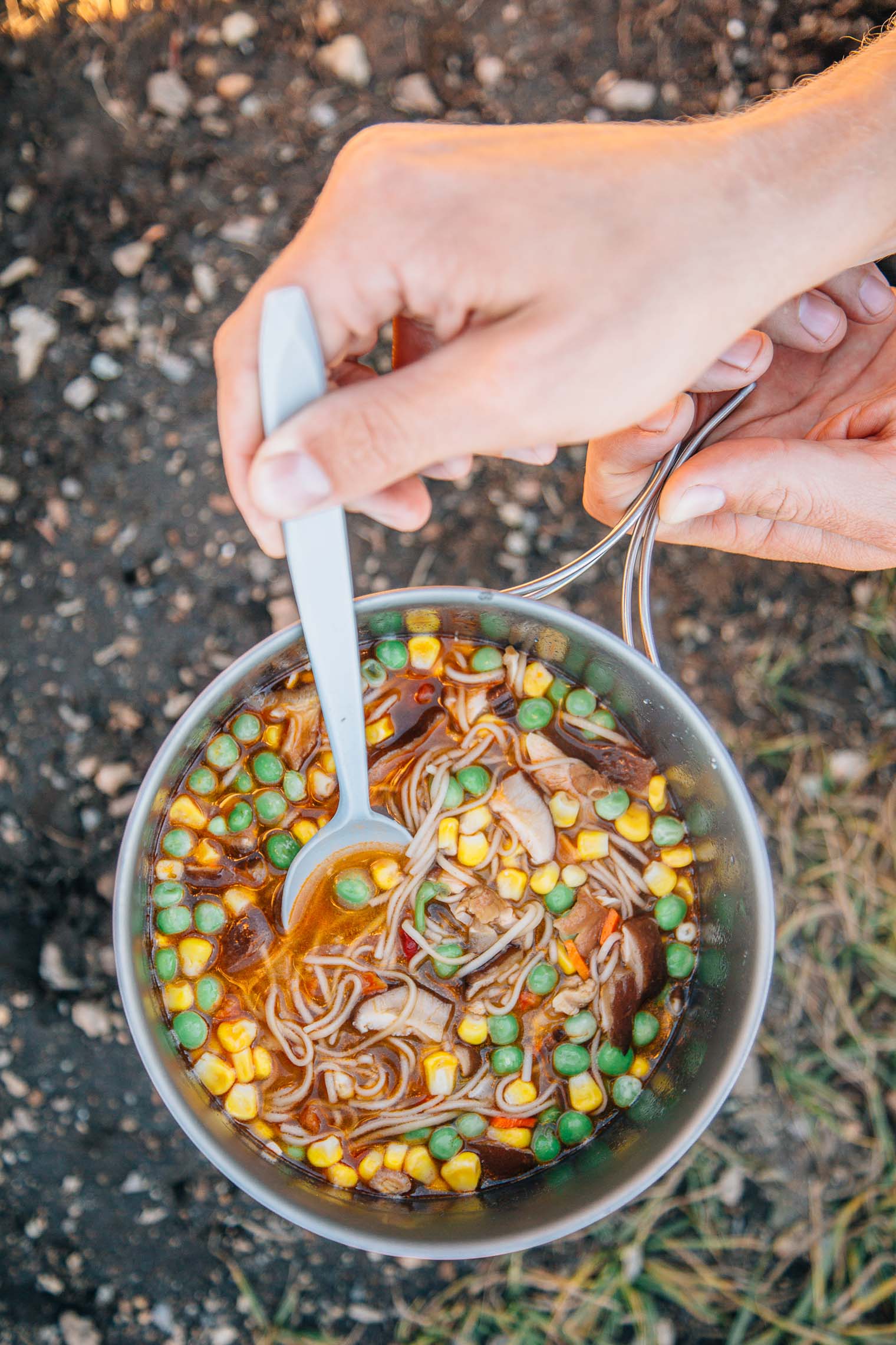 Michael stirring noodles and vegetables in a pot