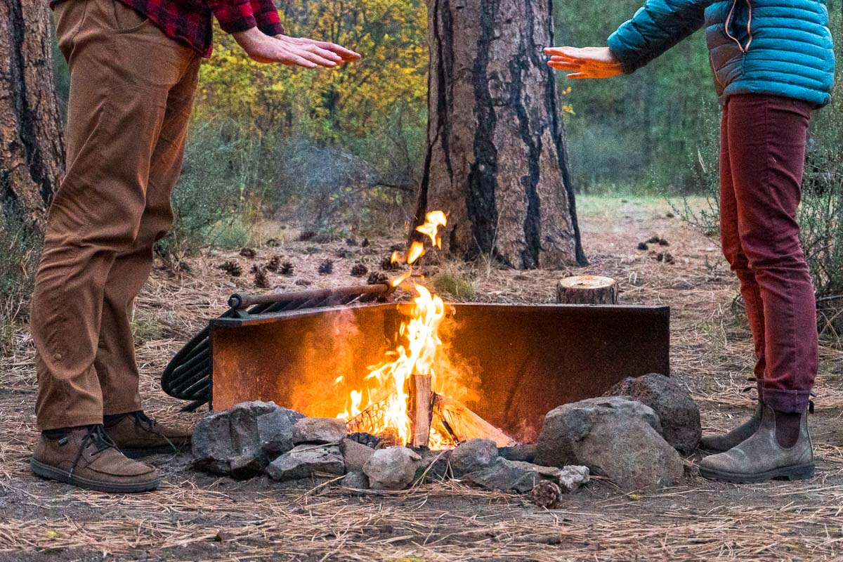 Two people holding their hands over a campfire