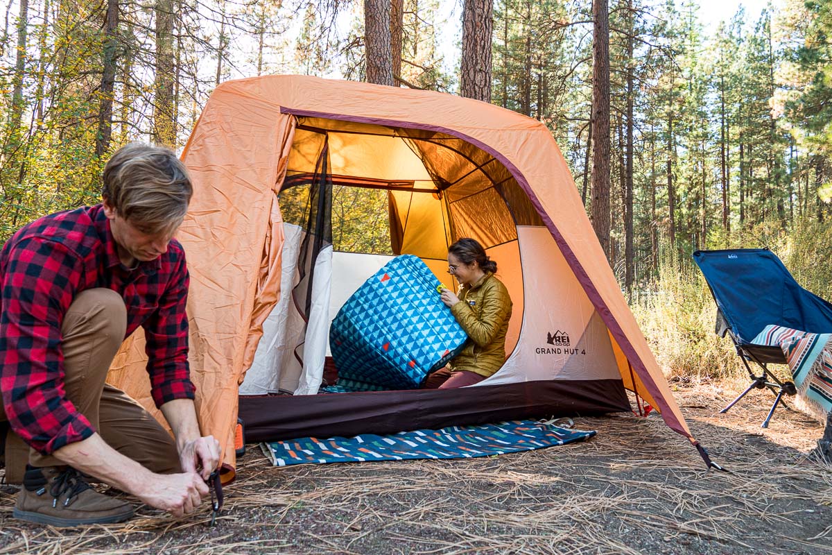 Michael adjusts a tent stake while Megan blows up a sleeping pad inside the tent