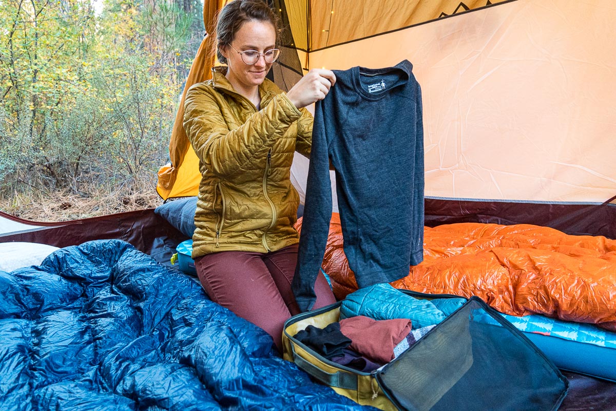 Megan lifting a long sleeve shirt out of her clothing storage bag