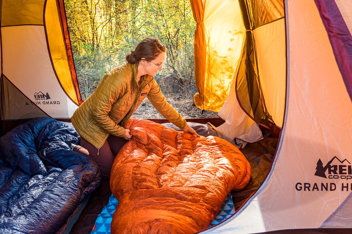 Megan sitting inside a tent spreading a sleeping bag out