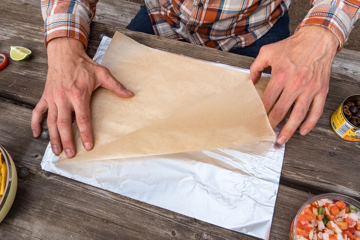 Michael laying a piece of parchment paper over a piece of foil