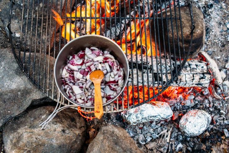 A pot of red onions over a campfire