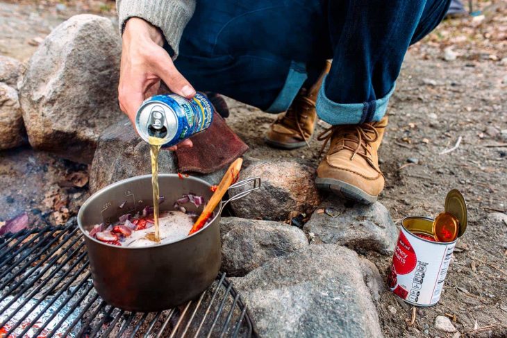 Michael pouring beer into a pot of chili