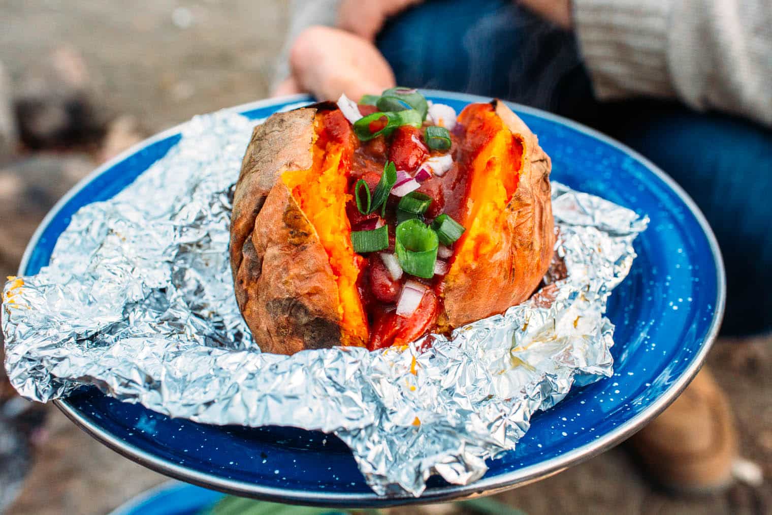 A sweet potato and chili in foil on a blue plate