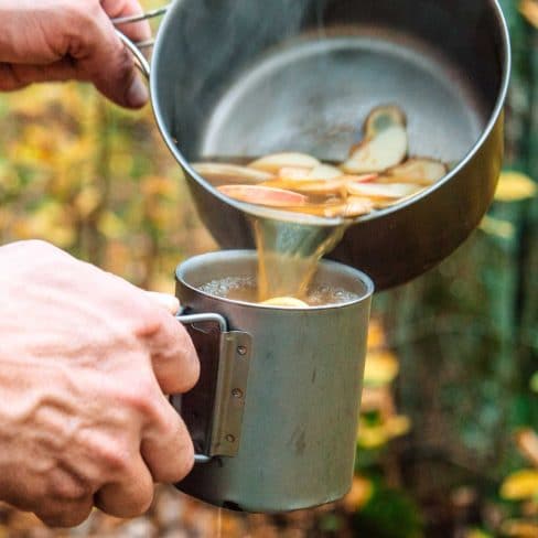 Michael pouring cider with ginger from a pot into a silver mug