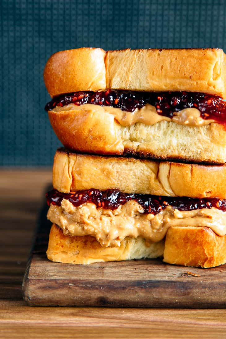 Brioche pb&j sandwich stacked on a wooden board