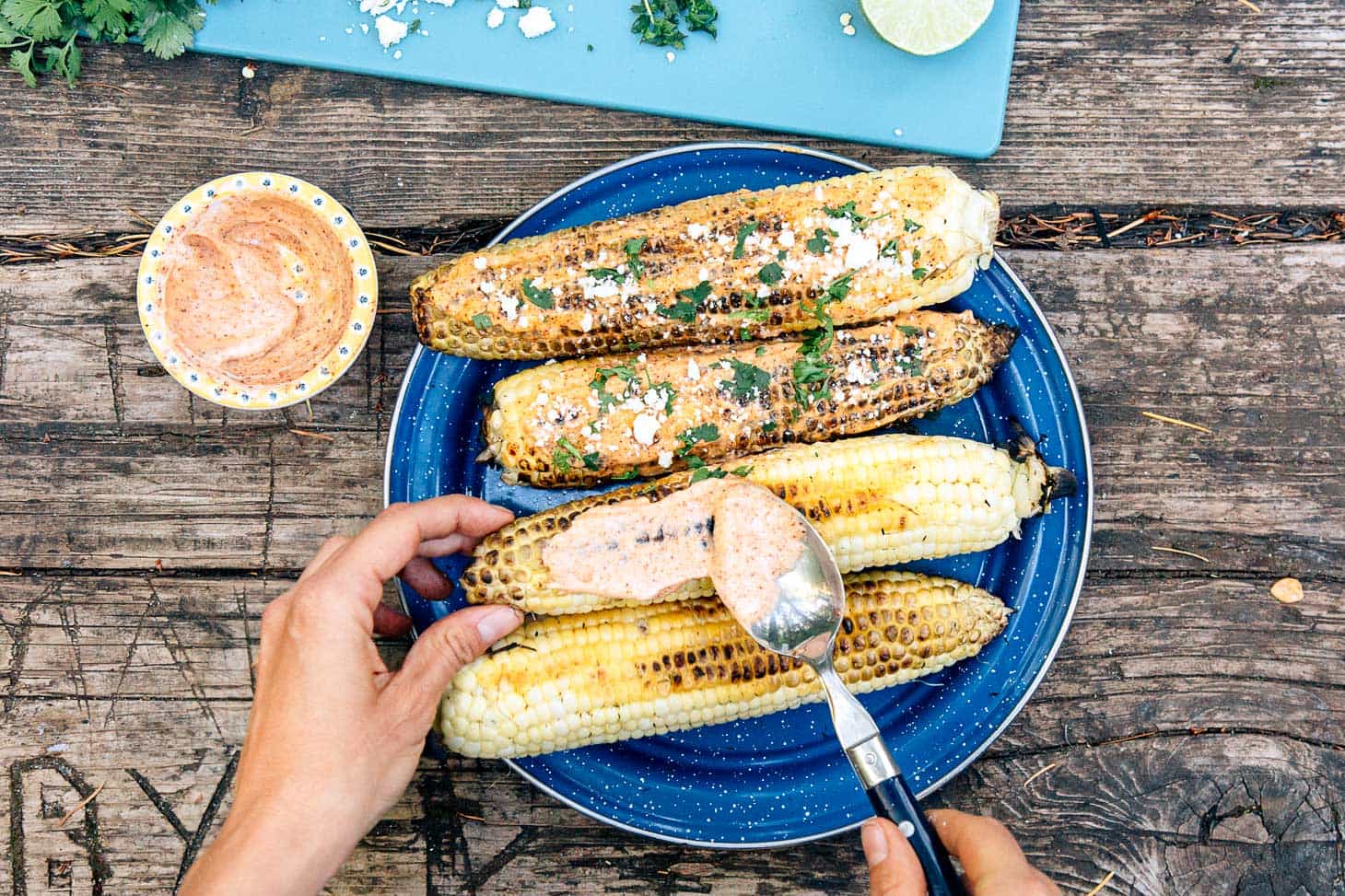 Making elote - grilled corn served with spicy mayo and Cojita cheese - a perfect camping appetizer.