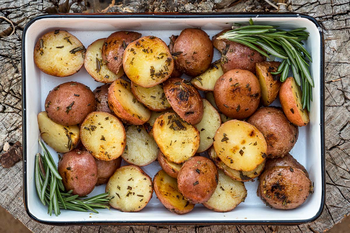 Grilled potatoes in a baking dish garnished with rosemary