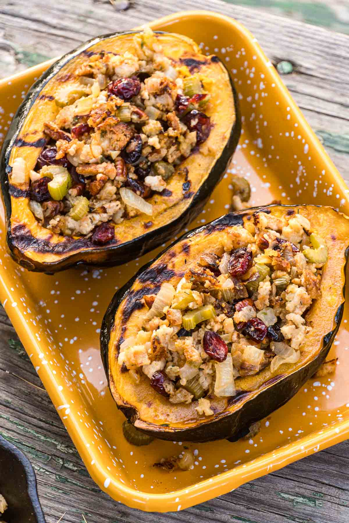 Stuffed acorn squash halves in a yellow enamel dish.