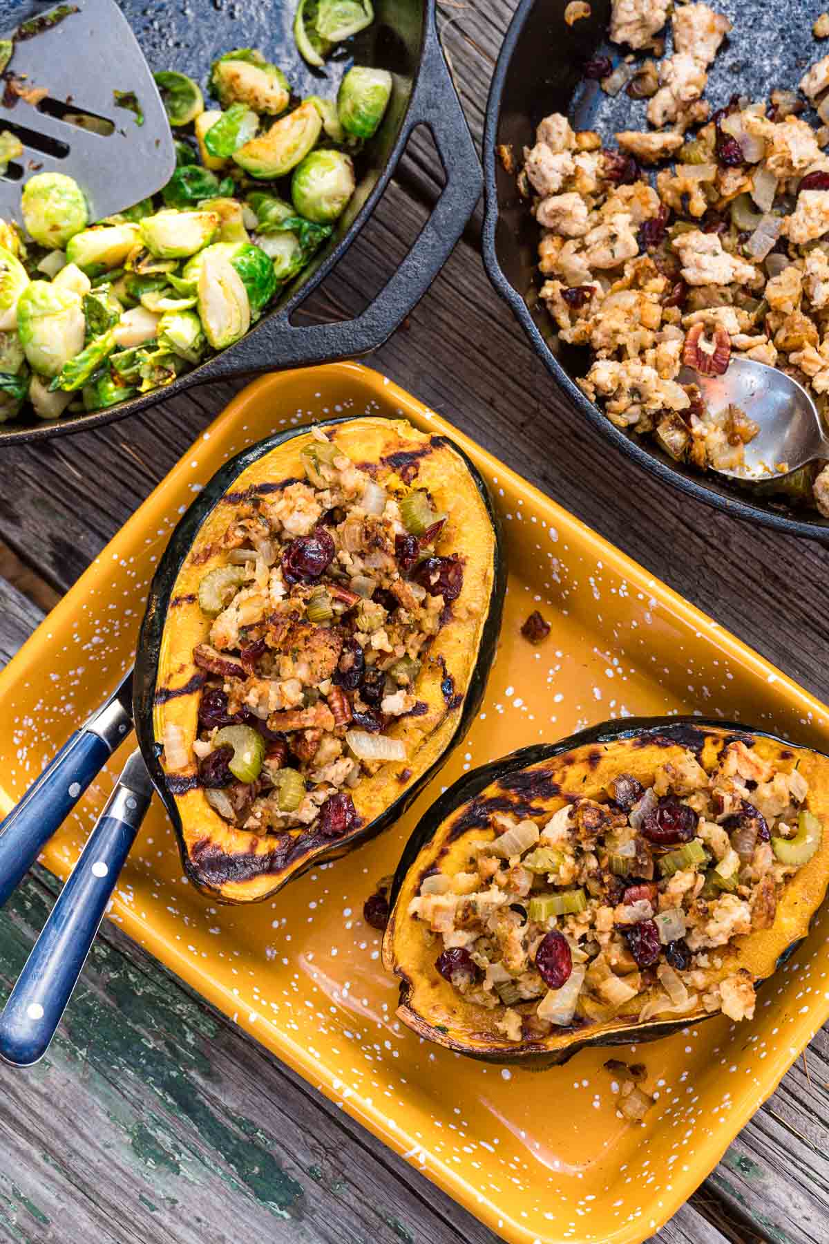 Stuffed acorn squash halves in a yellow enamel dish.