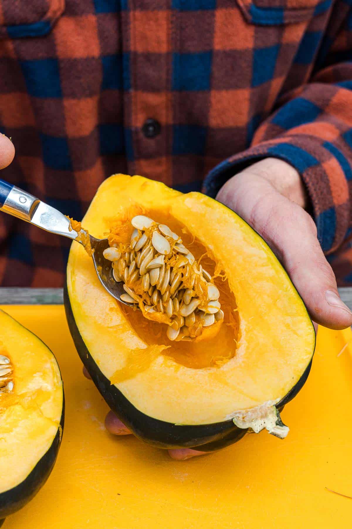 Scooping seeds out of half an acorn squash.