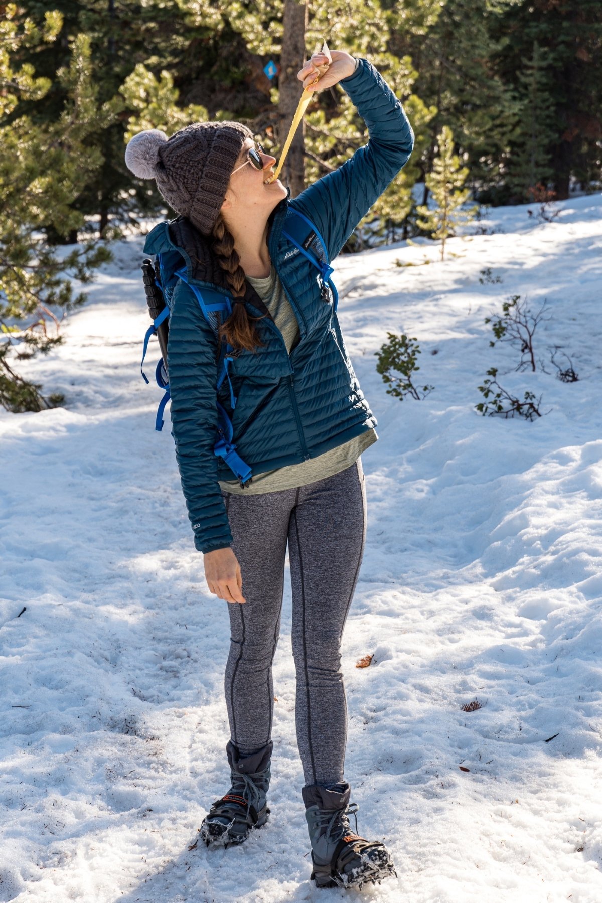 Megan eating a fruit leather on a snow covered trail