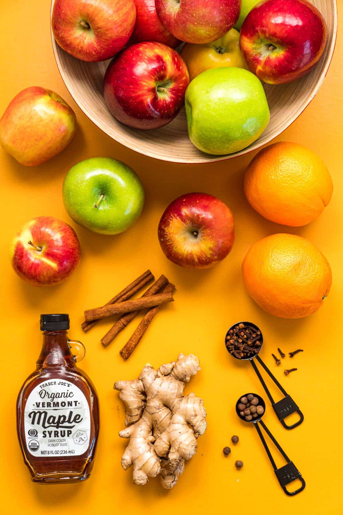 Ingredients to make apple cider displayed on a yellow background.