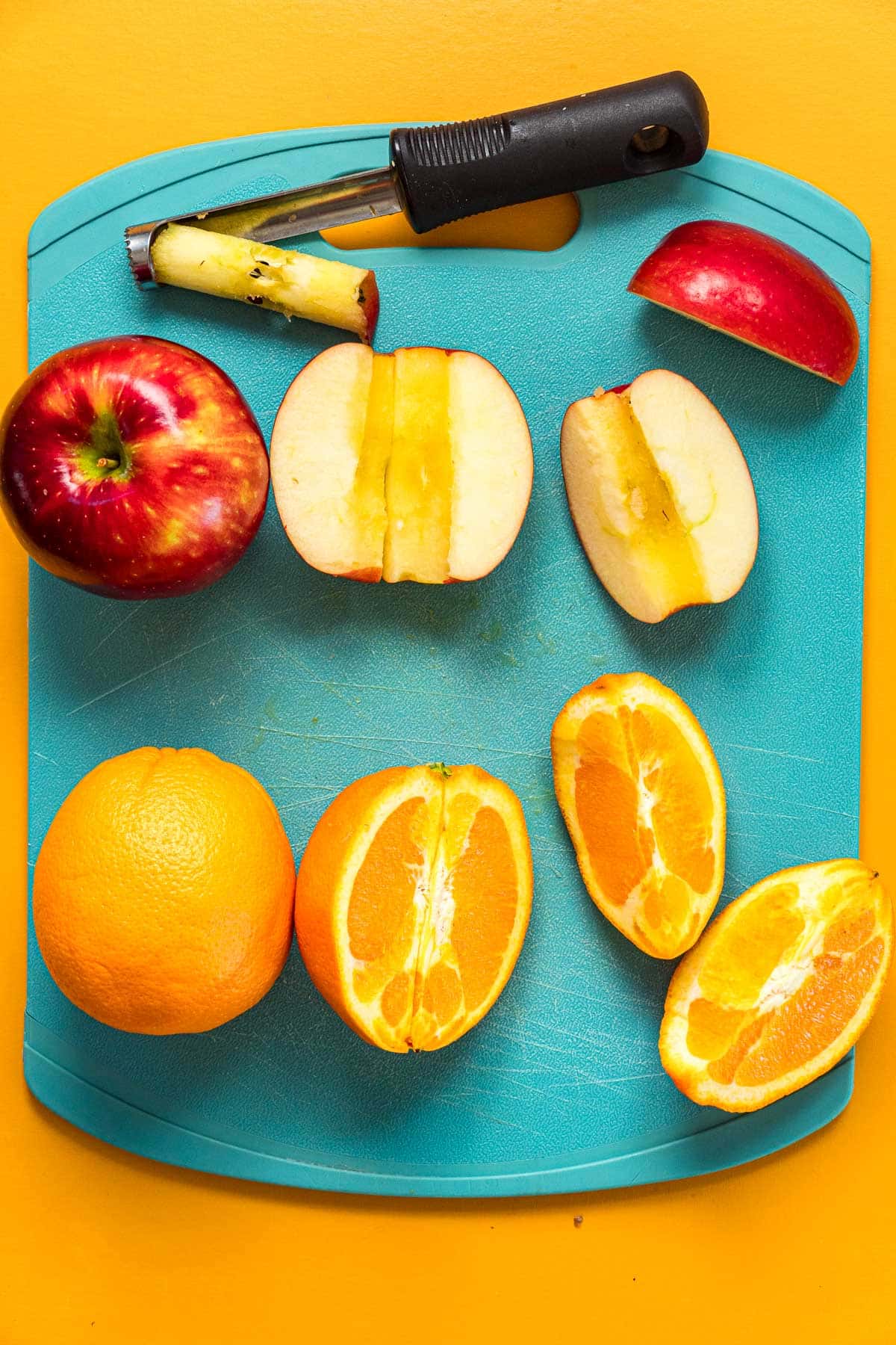 Apples and oranges quartered on a cutting board.