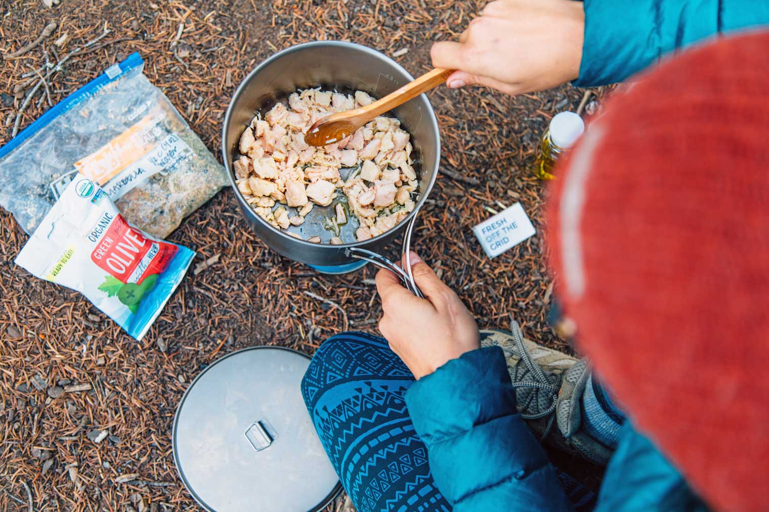 Megan heating pieces of chicken in a backpacking pot