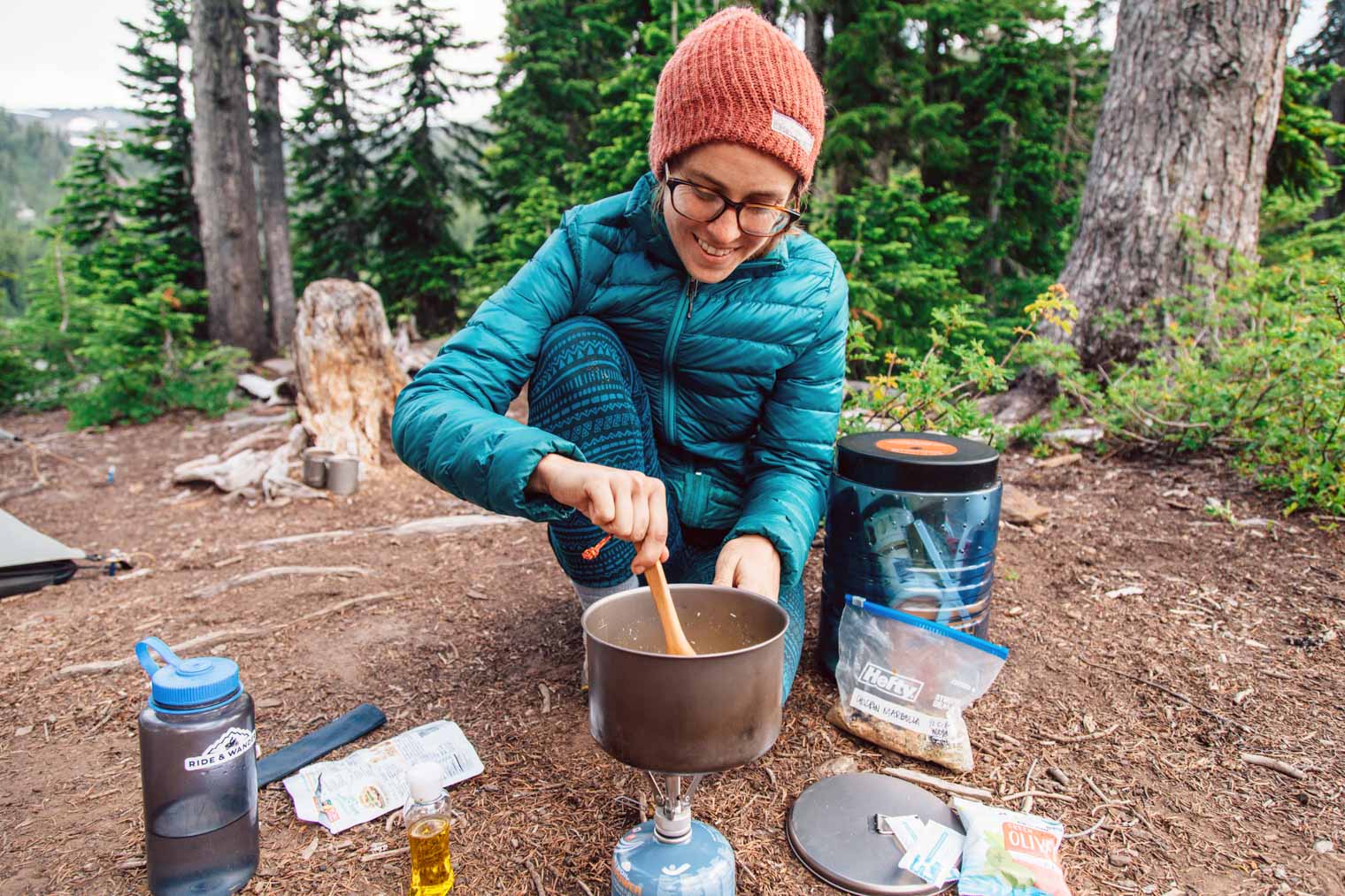 Megan stirring the contents of a pot that is on a backpacking stove